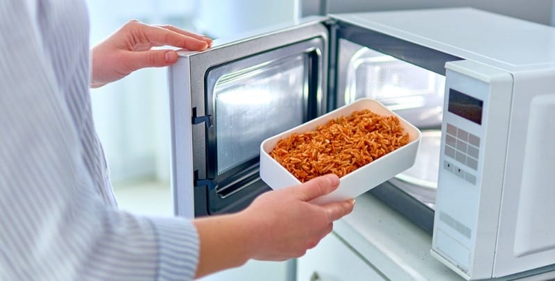 A woman uses a microwave oven
